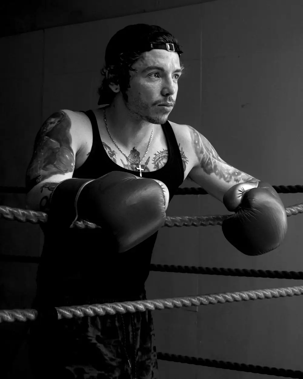 Ilustrační foto: tetovaný boxer opřený o provazy ringu